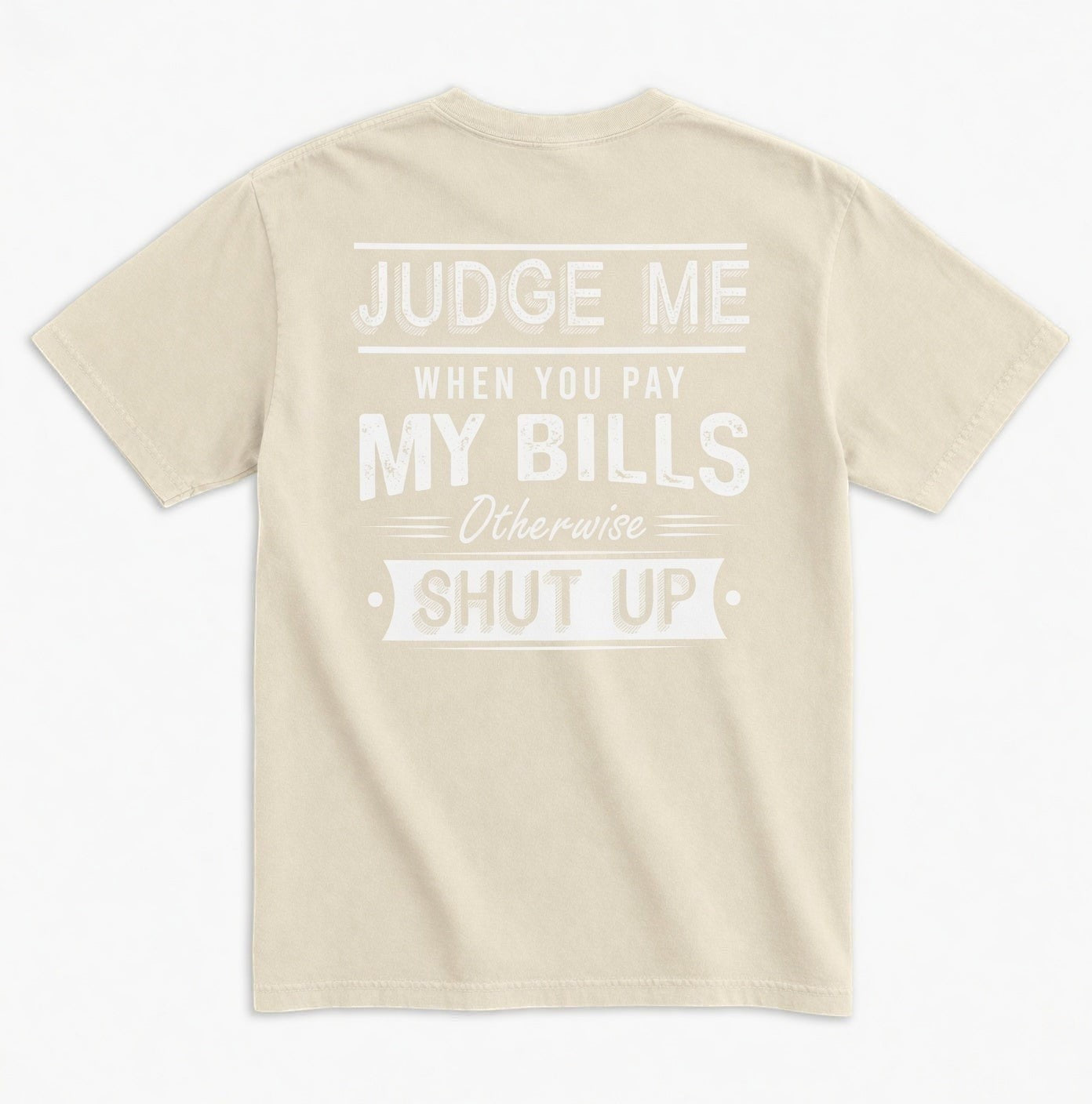 TrendyShift.Com beige unisex graphic tee with white distressed typography on the back reading Judge Me When You Pay My Bills. Otherwise SHUT UP.