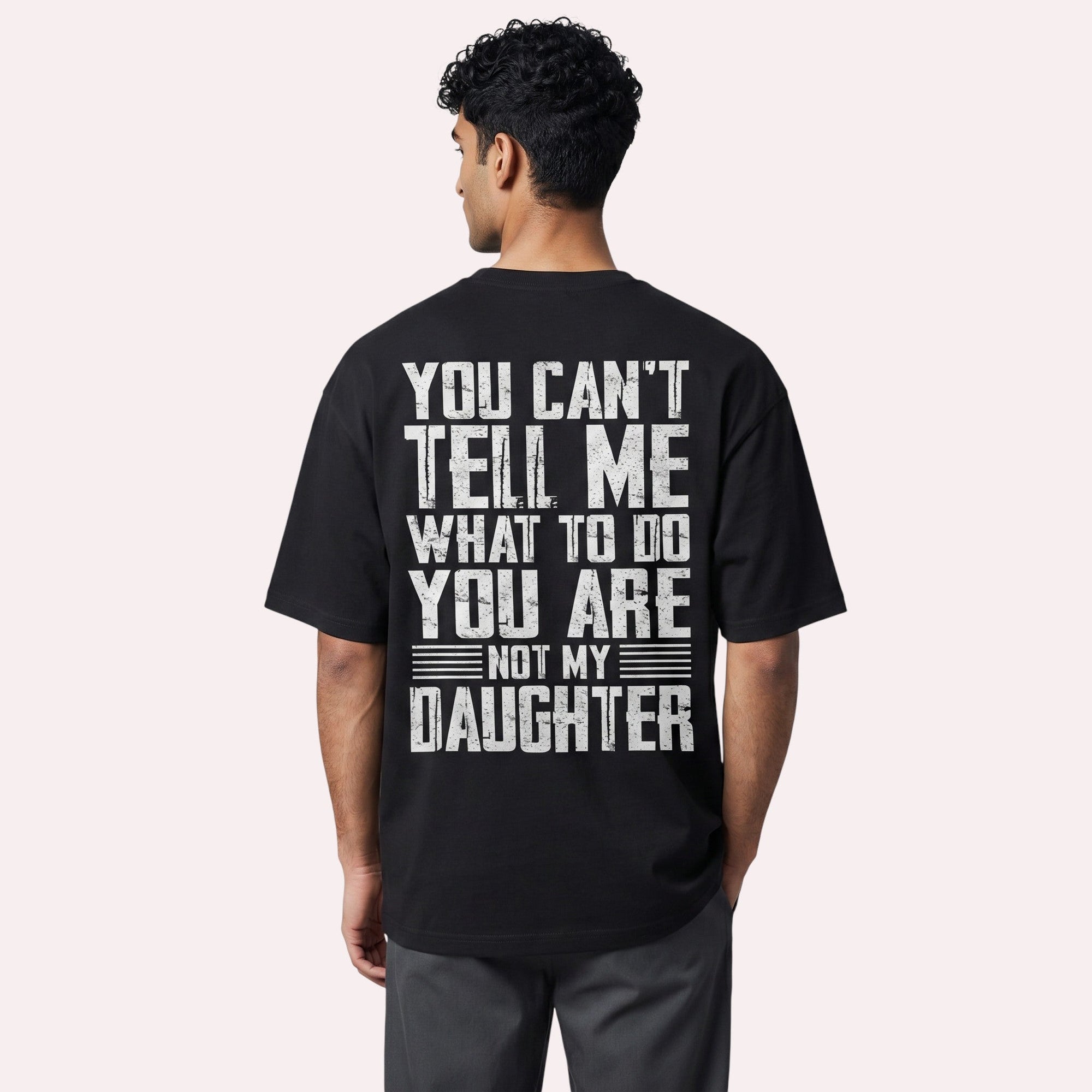 TrendyShift.Com black cotton graphic t-shirt with distressed white typography on the back, worn by a man.
