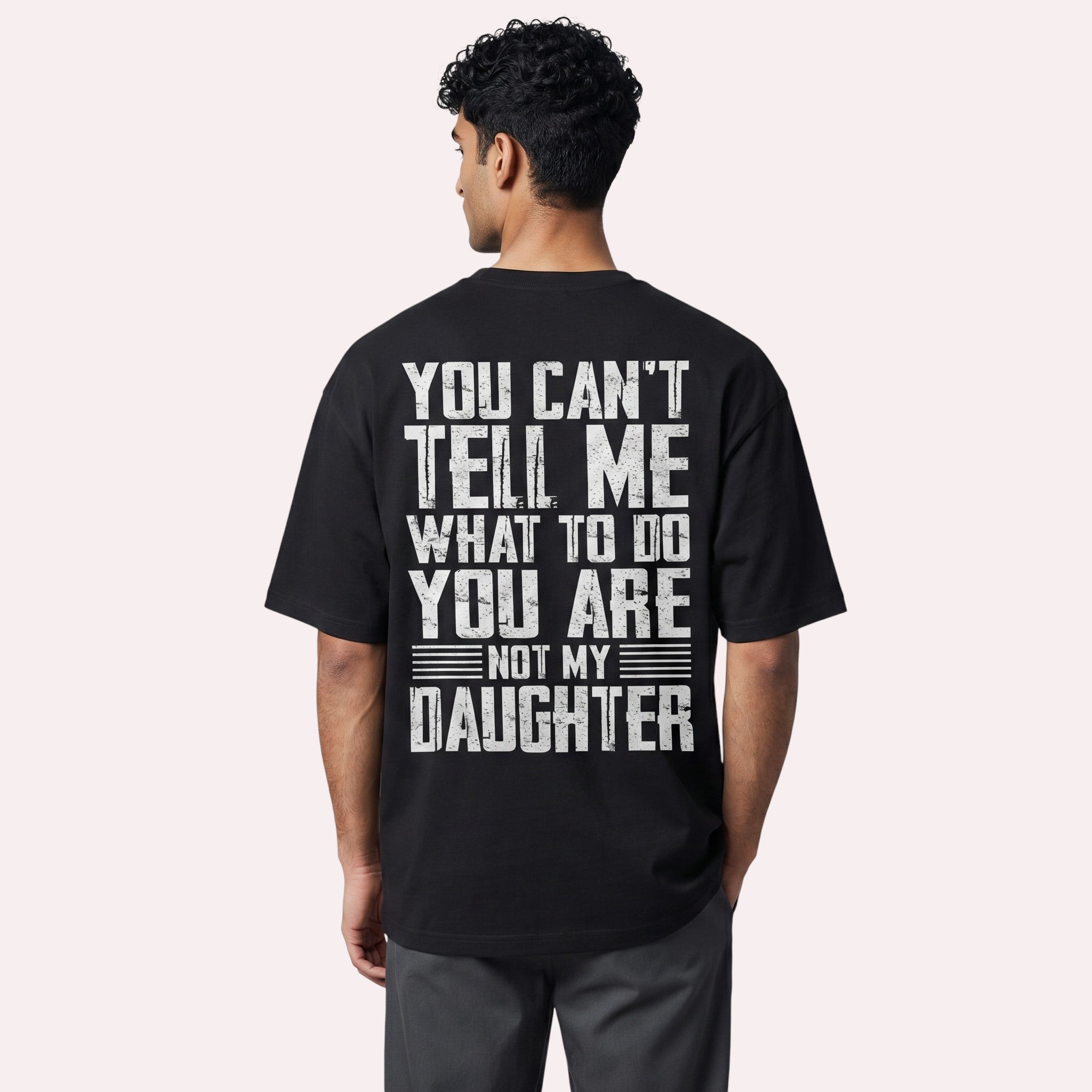 TrendyShift.Com black cotton graphic t-shirt with distressed white typography on the back, worn by a man.