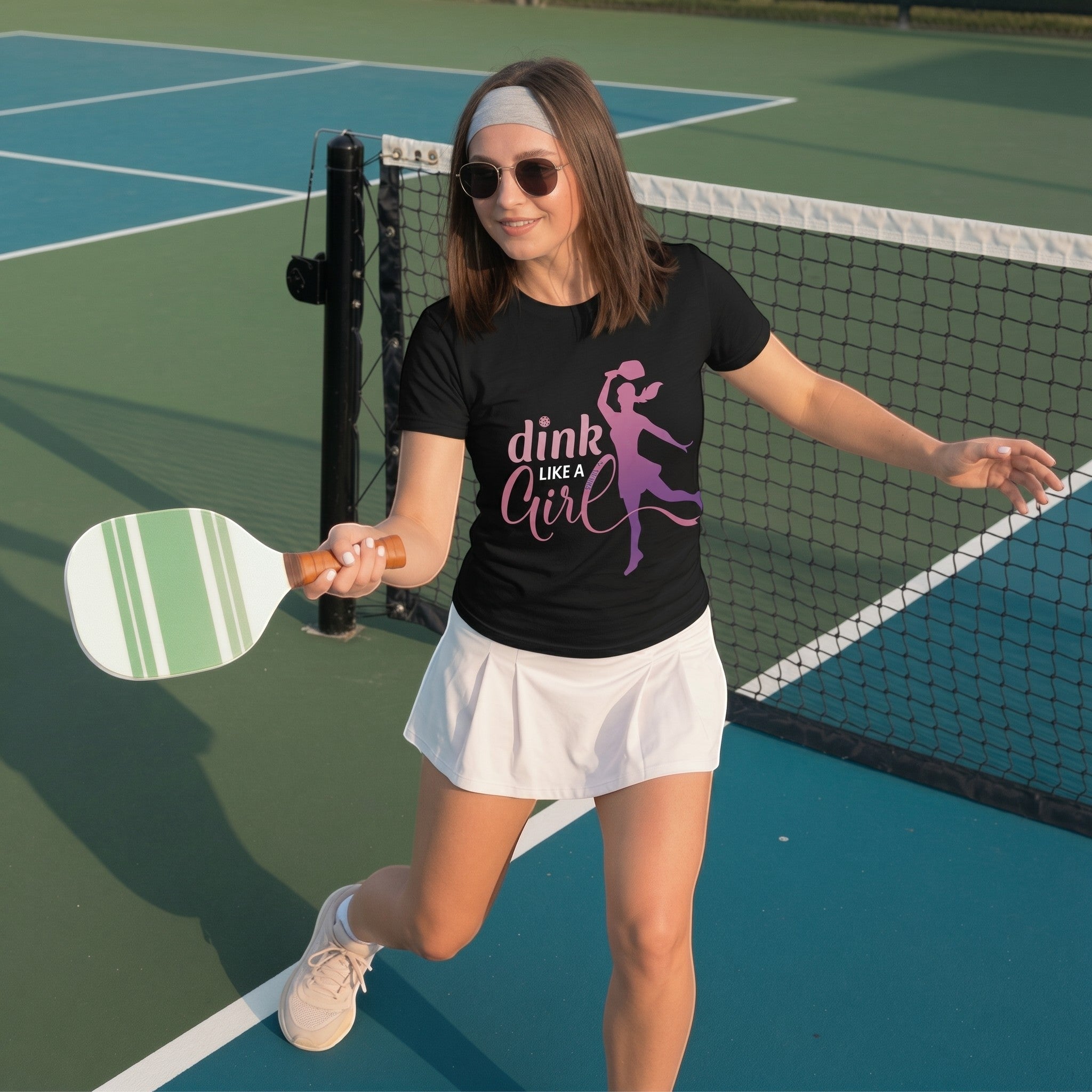 TrendyShift.Com black cotton t-shirt with Dink Like a Girl pickleball graphic worn by a woman on a pickleball court
