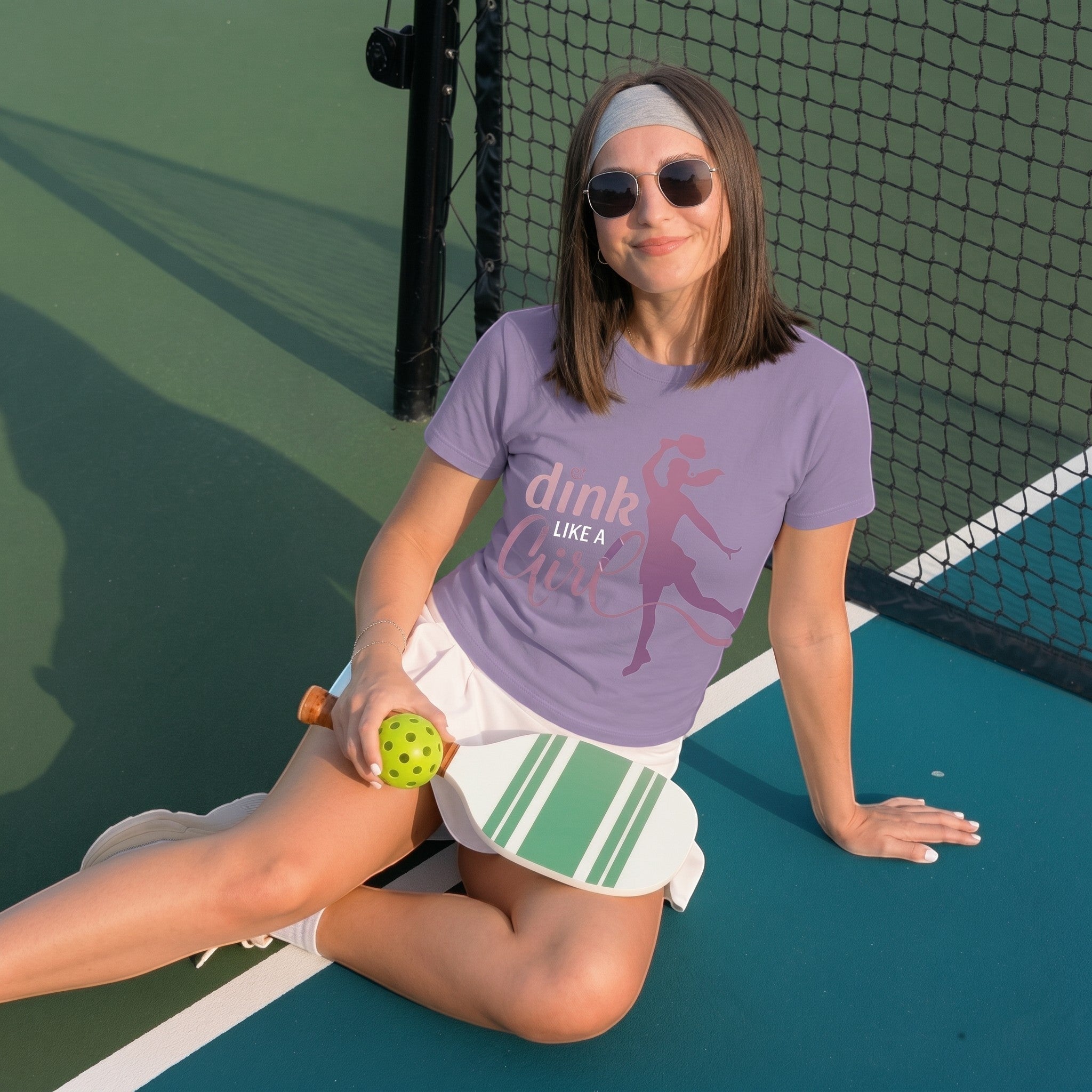 TrendyShift.Com lavender short sleeve cotton tee with Dink Like a Girl pickleball graphic worn by a woman on a court.