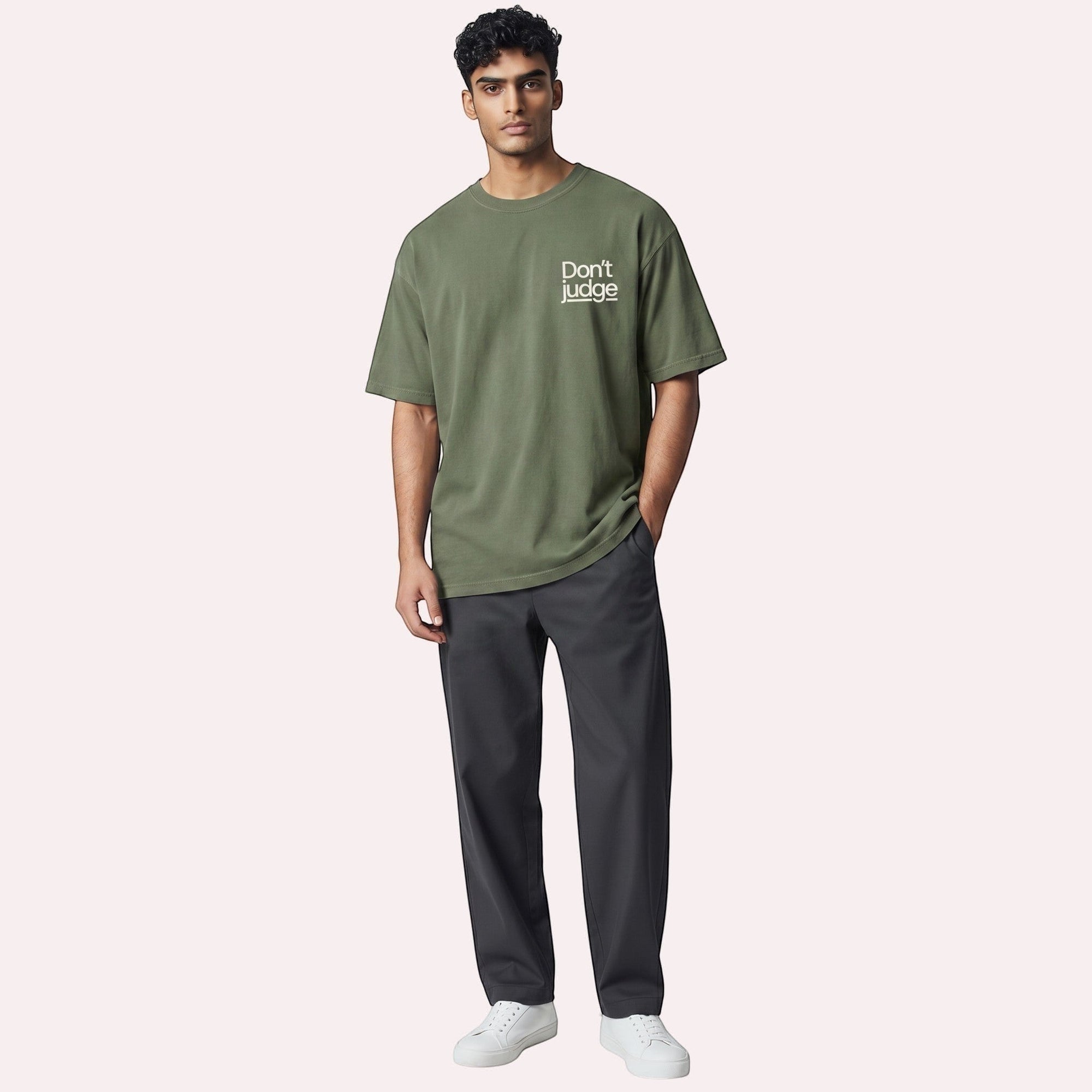 TrendyShift.Com olive green oversized graphic t-shirt with Don't Judge text on chest worn by a male model