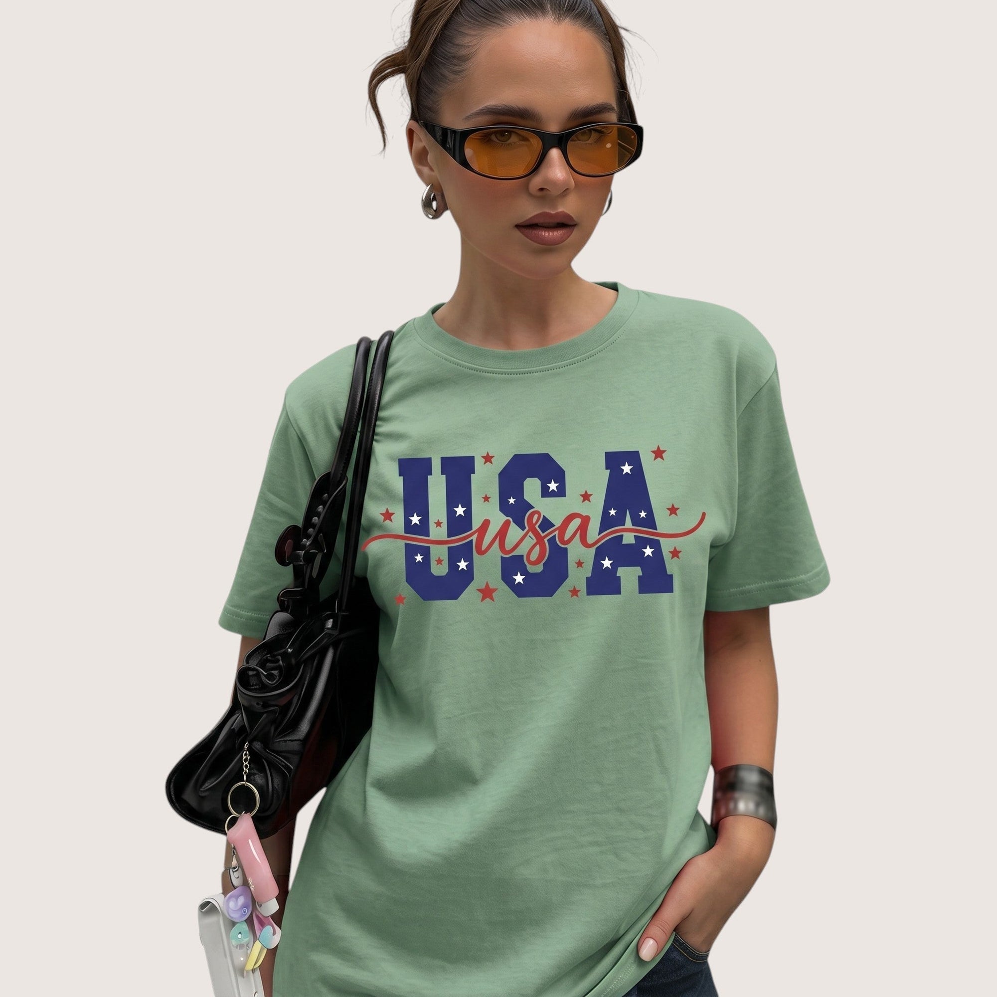 TrendyShift.Com sage green unisex cotton t-shirt with USA patriotic graphic print worn by a woman with sunglasses